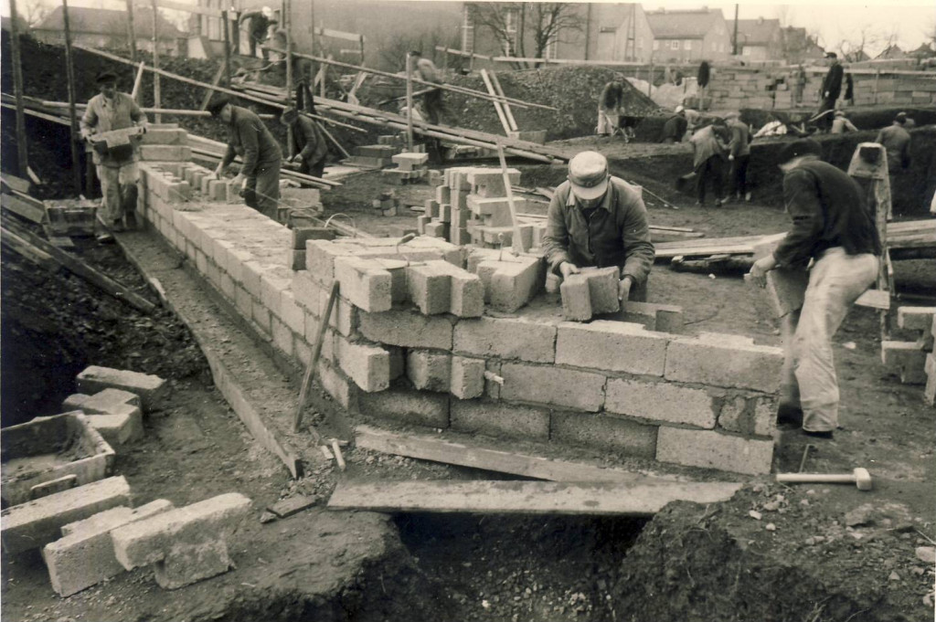 Die ersten Mauersteine auf dem Fundament werden gesetzt.