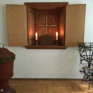 in die Wand eingelassen ist ein verschließbarer Wandaltar, der die wichtigsten Stationen der Heilsgeschichte bildlich darstellt.